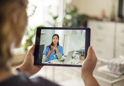 Over the shoulder shot of a patient talking to a doctor using of a digital tablet